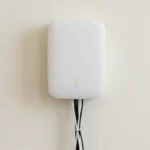 Photograph of a white NBN-style FTTP connection box mounted on a clean cream wall of an Australian home with cables routing behind the skirting