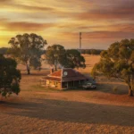 Rural Australian farmhouse with a satellite internet dish on the roof and a mobile tower on the horizon
